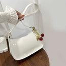 Bolso baguette charol blanco con silueta curva y2k sostenido en mano