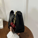Bolso baguette charol negro de perfil con dije cerezas estilo coquette urbano
