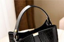 Detalle textura cocodrilo brillante y cierre metálico dorado en bolso bucket mujer