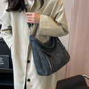 Mujer usando bolso cruzado hobo beige con look invernal de sweater de lana gris