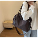 Mujer usando bolso de hombro de nailon color khaki con look casual de sweater y jeans