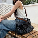 Mujer usando bolso motociclista como bandolera en look casual Y2K con jeans anchos