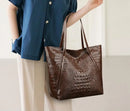 Mujer usando bolso tote cocodrilo negro con look casual elegante de jeans y blusa