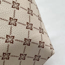 Detalle de la estampa monograma flores marrones sobre cuero PU beige texturizado