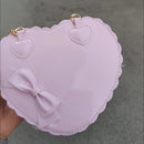 Detalle de moño 3D y borde festoneado en cartera corazón charol rosa