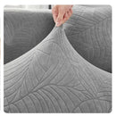 Detalle de textura jacquard con relieve de hojas en funda para sofá gris premium