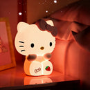 Lámpara nocturna Hello Kitty encendida en mesita con luz cálida suave