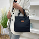 Lonchera térmica negra estilo cartera usada por mujer con blazer blanco