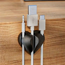 Organizador de cables con forma de corazón sosteniendo cables en el escritorio