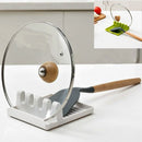 Porta cuchara para cocina antideslizante con espátula y tapa de olla apoyadas en la mesada